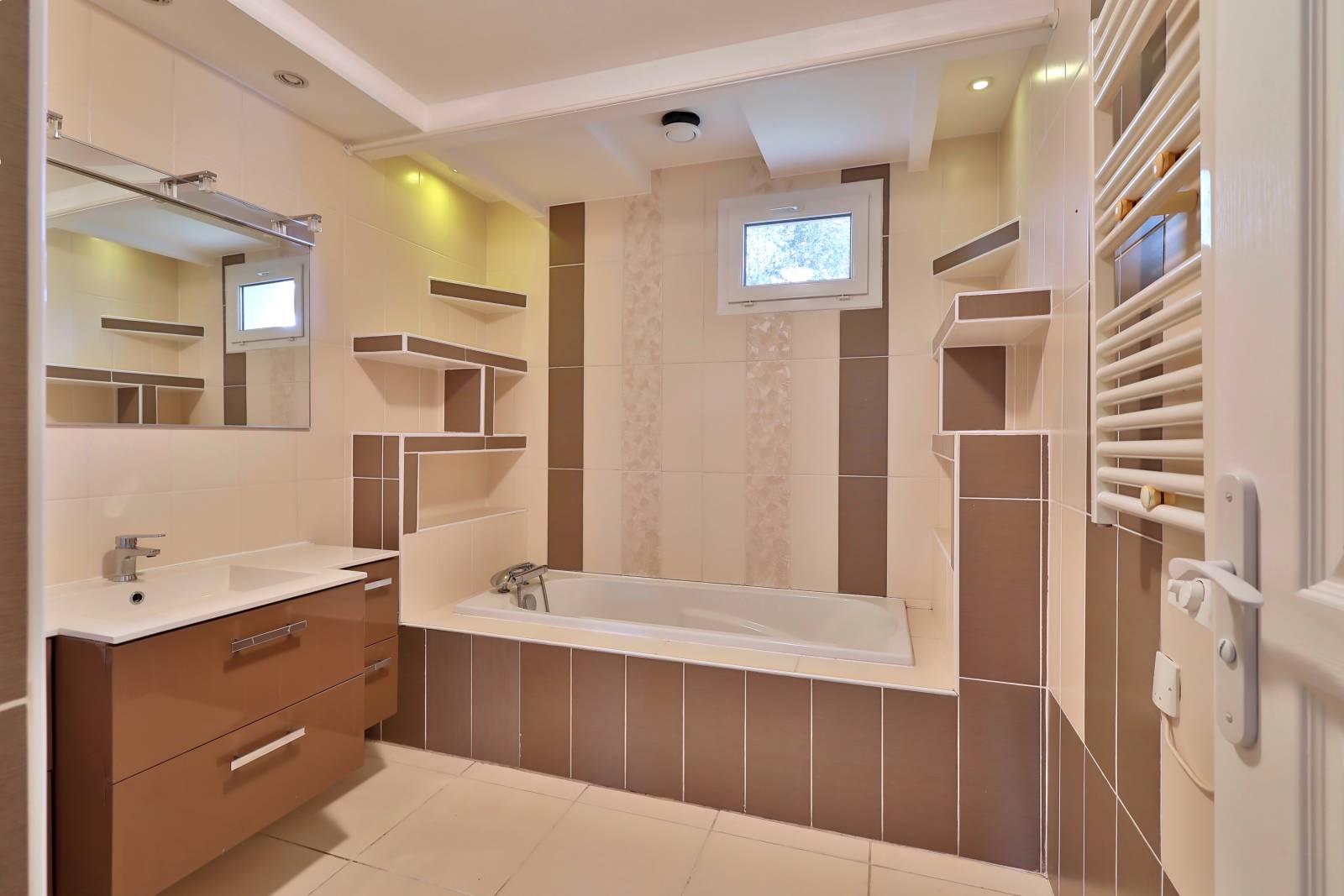 Grande salle de bains avec baignoire, meuble vasque et rangements intégrés – espace lumineux et fonctionnel dans maison familiale à Vaulx-en-Velin
