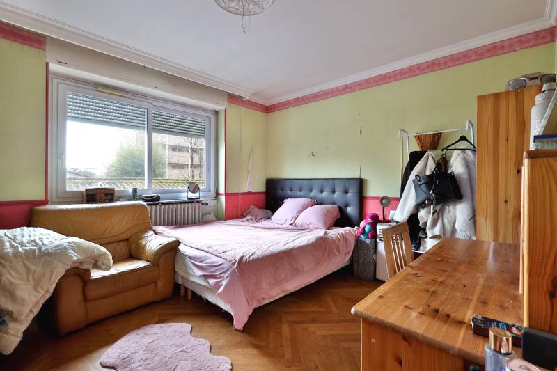 Chambre lumineuse avec parquet en chevron, offrant un fort potentiel après rafraîchissement