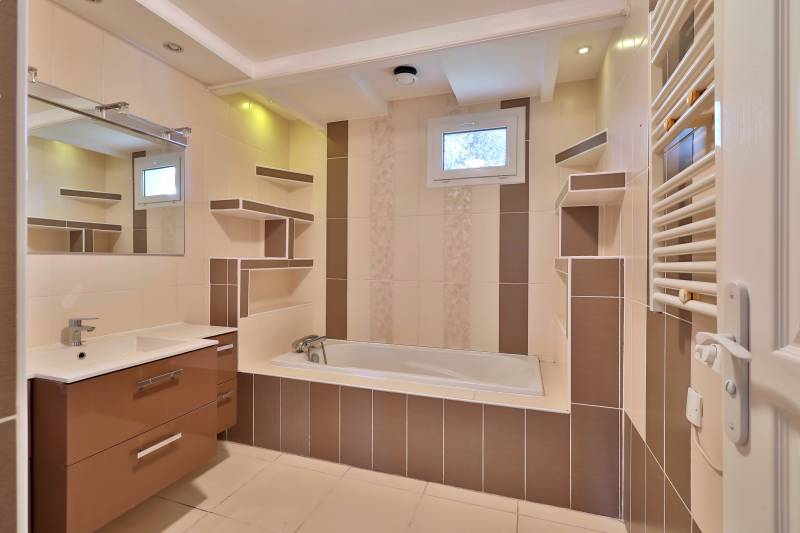 Grande salle de bains avec baignoire, meuble vasque et rangements intégrés – espace lumineux et fonctionnel dans maison familiale à Vaulx-en-Velin