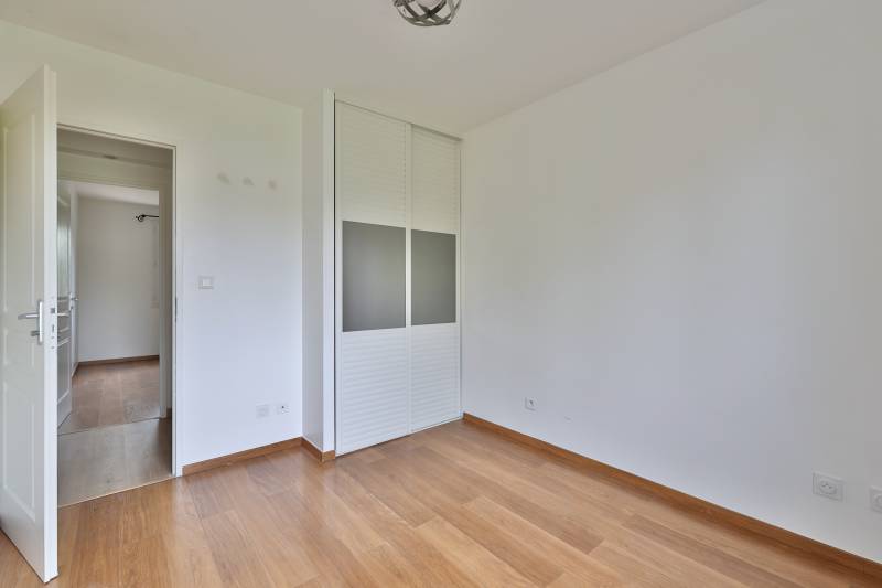 Chambre lumineuse exposée est avec placard mural intégré et parquet bois – espace nuit fonctionnel et confortable dans maison familiale à Vaulx-en-Velin